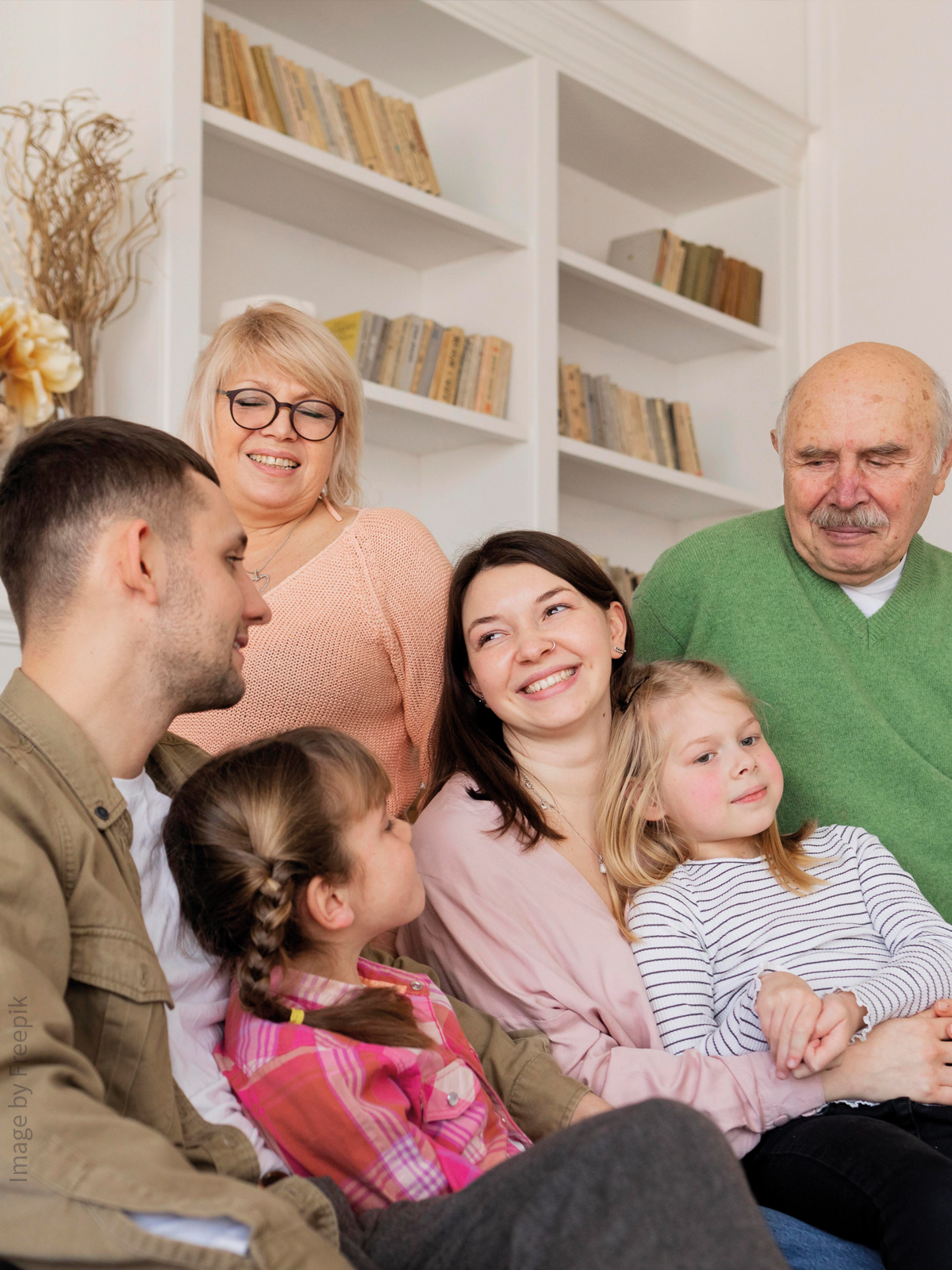Eine Familie, bestehend aus drei Generationen, sitzt im Wohnzimmer und ist glücklich